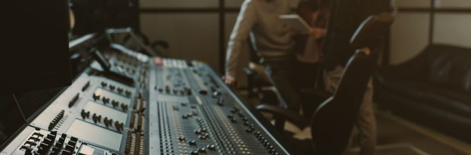 blurred group of musicians spending time at recording studio with graphic equalizer